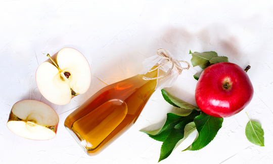 Apple cider vinegar with the mother and apples on a table