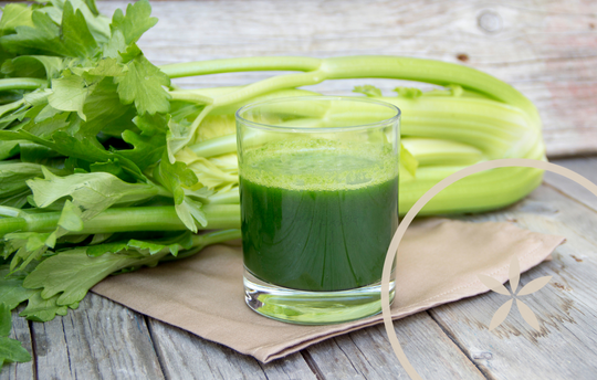 Celery juice and celery stalks on a table with paper napkins